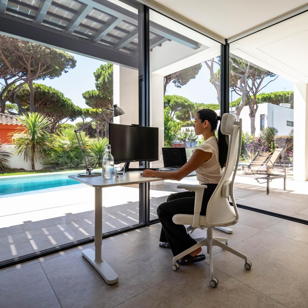 La mujer trabaja a distancia en un espacio de trabajo con vistas a la piscina en una villa de Chiclana de la Frontera, Andalucía