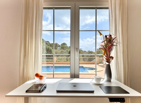 Blick vom optional buchbaren Arbeitsplatz im unteren Wohnzimmer mit schönem Blick auf den Pool und die Landschaft