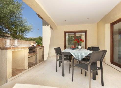 Sitzgruppe auf der überdachten Terrasse mit Holzkohlegrill