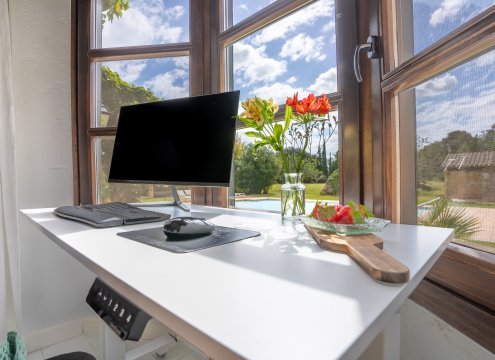 Professioneller Arbeitsbereich (optional buchbar) im Hauptschlafzimmer mit schönem Blick auf den Pool und den Garten
